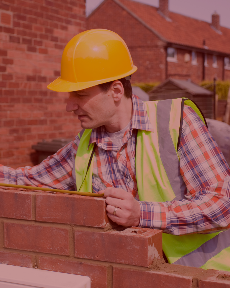 builders in hard hats and hi-vis reviewing brickwork on building site